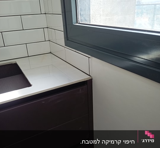 אריחי קרמיקה חדשים על קיר מטבח ליד חלון
